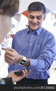 Man Using Contactless Payment App On Smart Watch In Store