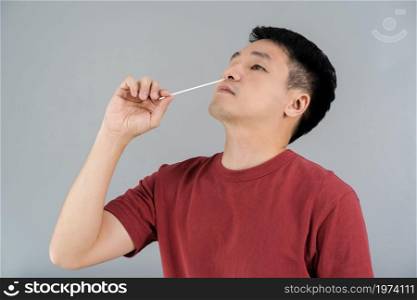 man using coronavirus(covid-19) rapid antigen self test kit (atk) at home with a cotton nasal swab