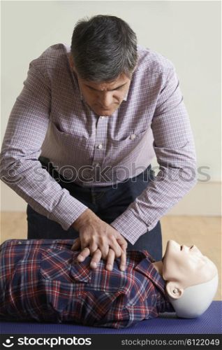 Man Using CPR Technique On Dummy In First Aid Class