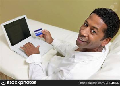 Man Using Credit Card to Make Purchase with Laptop