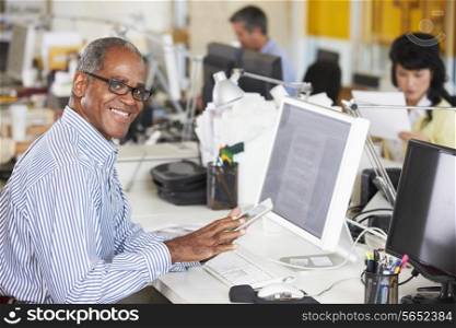 Man Using Digital Tablet In Busy Creative Office