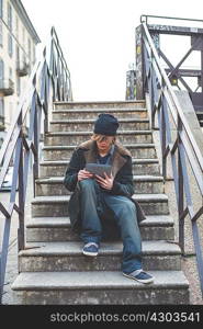 Man using digital tablet on steps, Milan, Italy