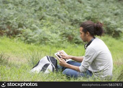 Man Using Digital Tablet Whilst Hiking In Countryside