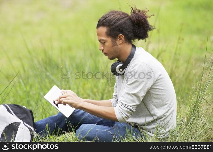 Man Using Digital Tablet Whilst Hiking In Countryside