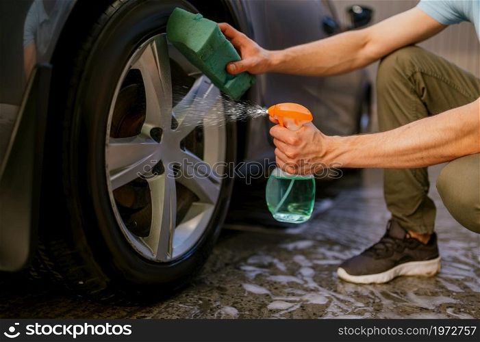 Man using disk cleaner spray, hand car wash station. Car-wash industry or business. Male person cleans his vehicle from dirt outdoors. Man using disk cleaner spray, hand car wash
