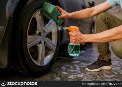 Man using disk cleaner spray, hand car wash station. Car-wash industry or business. Male person cleans his vehicle from dirt outdoors. Man using disk cleaner spray, hand car wash