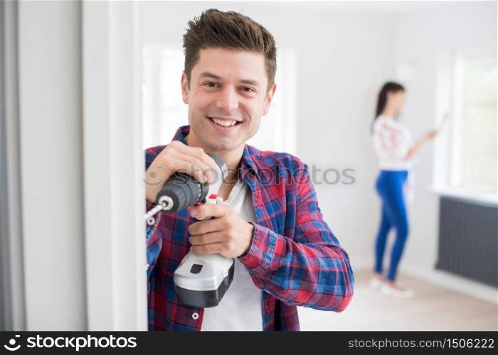 Man Using Electric Drill As Couple Renovate Property Together