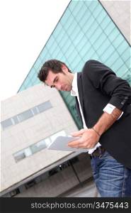 Man using electronic tablet in front of modern building