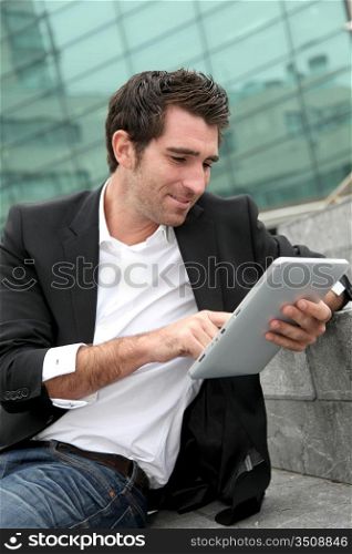 Man using electronic tablet in front of modern building