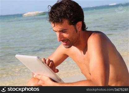 Man using electronic tablet on the beach