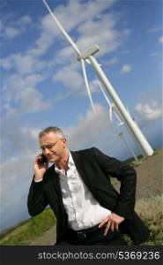 Man using his cellphone next to wind turbines