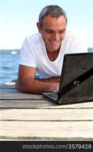 Man using his laptop on jetty