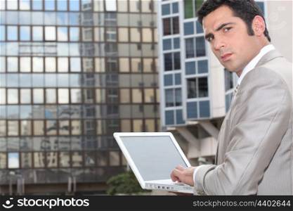 Man using his laptop outside an office block