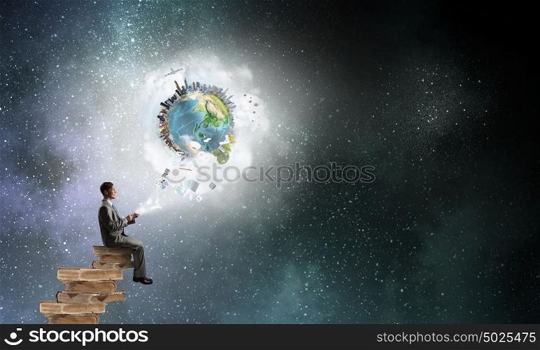 Man using his mobile phone. Young businessman sitting on pile of books with mobile phone in hand. Elements of this image are furnished by NASA