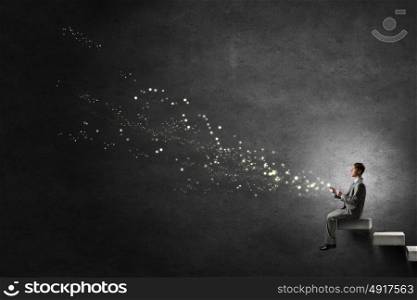 Man using his mobile phone. Young businessman sitting on steps with mobile phone in hand