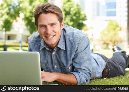 Man using laptop in city park
