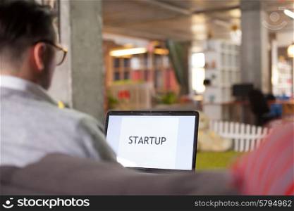 Man using laptop in startup office. Startup word on screen
