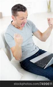 man using laptop making triumphant gesture