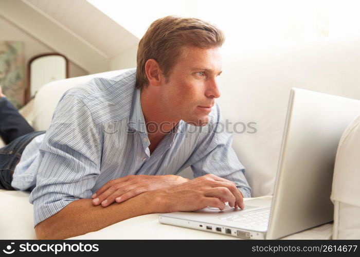 Man Using Laptop Relaxing Sitting On Sofa At Home