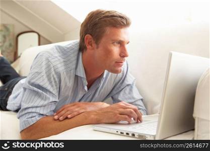 Man Using Laptop Relaxing Sitting On Sofa At Home