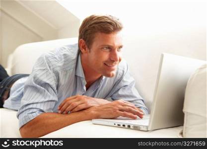 Man Using Laptop Relaxing Sitting On Sofa At Home