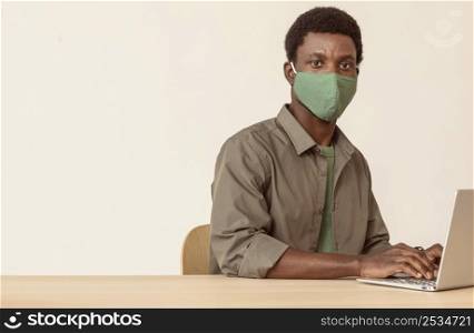 man using laptop wearing green medical mask