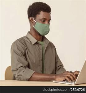 man using laptop wearing mask