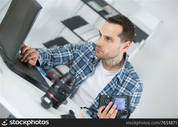 Man using laptop while repairing camera