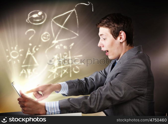 Man using laptop. Young businessman looking shocked into tablet pc