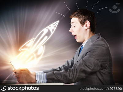 Man using laptop. Young businessman looking shocked into tablet pc