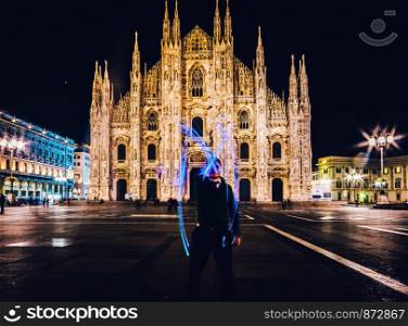 Man using light painting long exposure draws an M letter in front of the Milan Cathedral, Milan, Italy.. Man using light painting long exposure draws an M letter in front of the Milan Cathedral, Milan, Italy