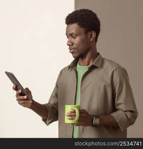 man using mobile phone holding green mug