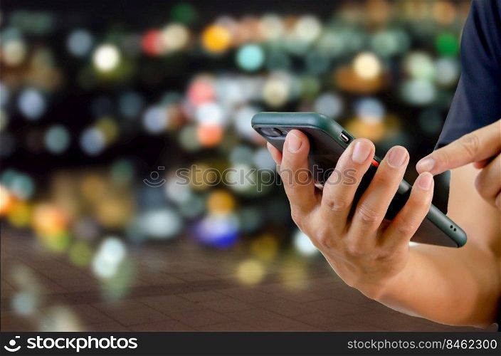 man using mobile phone in the street in the background night light.