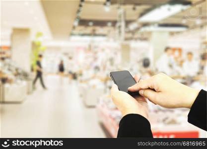 Man using mobile phone over blurred superstore background