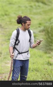 Man Using Mobile Phone Whilst Hiking In Countryside