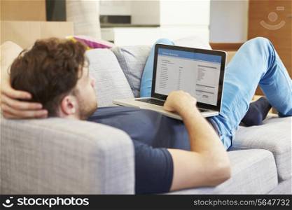 Man Using Online Banking Relaxing On Sofa