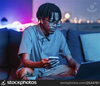 man using smartphone laptop while couch home
