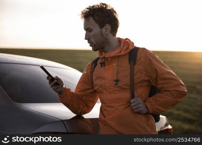 man using smartphone outdoors while road trip