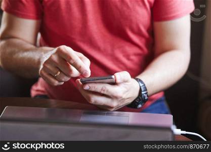 Man using smartphone working on laptop sitting at a desk