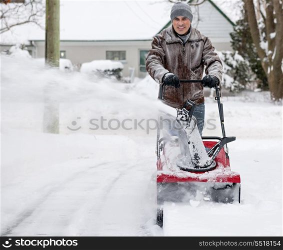 Man using snowblower in deep snow. Man using snowblower to clear deep snow on residential driveway after heavy snowfall