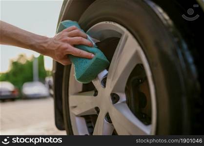 Man using sponge, hand car wash station. Car-wash industry or business. Male person cleans his vehicle from dirt outdoors. Man using sponge, hand car wash