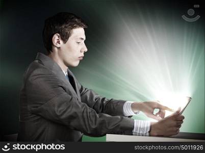Man using tablet pc. Young emotional businessman looking in tablet pc