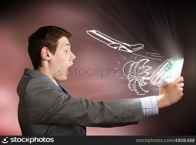 Man using tablet pc. Young emotional businessman looking shocked in tablet pc