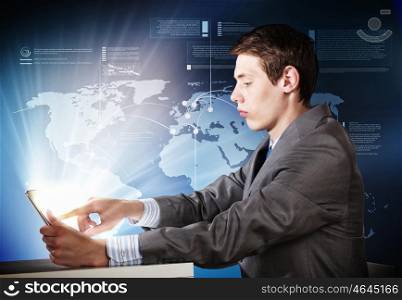 Man using tablet pc. Young emotional businessman looking thoughtfully in tablet pc