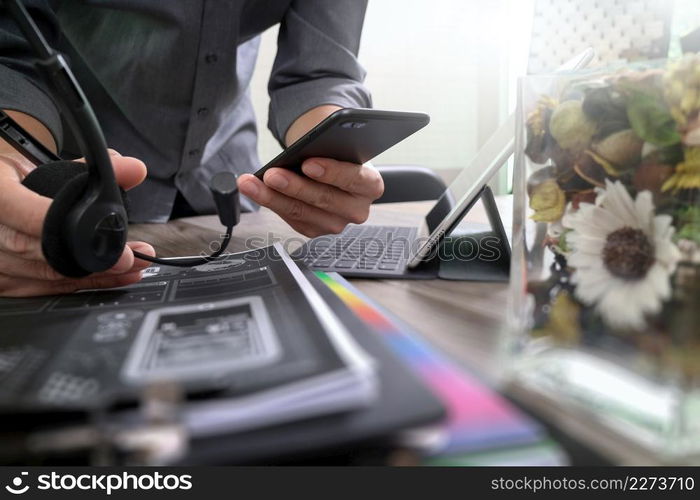 Man using VOIP headset with digital tablet computer docking keyboard,smart phone,concept communication, it support, call center and customer service help desk,vase flowers on wooden table