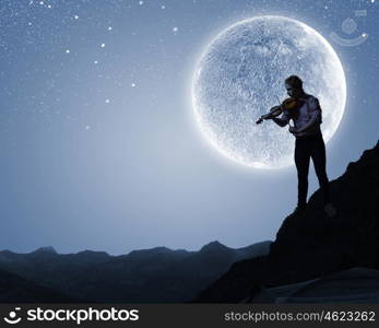 Man violinist. Silhouette of man playing violin at night