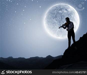 Man violinist. Silhouette of man playing violin at night