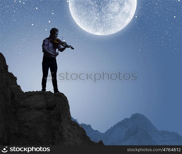 Man violinist. Silhouette of man playing violin at night