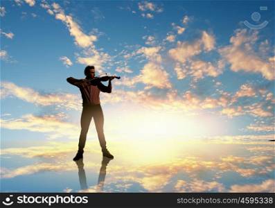 Man violinist. Silhouette of man playing violin at sunset
