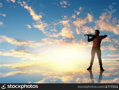 Man violinist. Silhouette of man playing violin high in sky